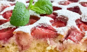 Puszyste ciasto jogurtowe z truskawkami, posypane cukrem pudrem i udekorowane miętą. Idealny sprawdzony przepis na letni deser.