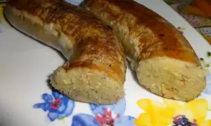 Dwie złociste kiszki ziemniaczane, pieczone do perfekcji, leżą na talerzu z kolorowymi kwiatami.