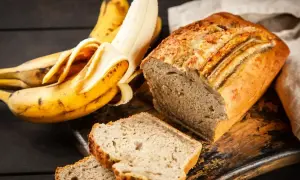 Wilgotne ciasto bananowe, obok dojrzałych bananów, kusi apetycznym wyglądem. Idealne na deser lub śniadanie.
