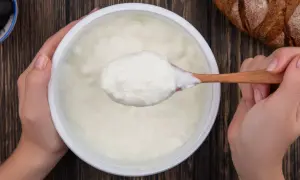 Gęsty, biały jogurt na drewnianej łyżce. To właśnie skyr, islandzki przysmak, który świetnie smakuje z chlebem i oliwkami.