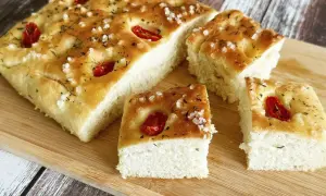 Puszysta, oryginalna włoska focaccia przepis z pomidorkami i solą morską, pokrojona na kawałki, gotowa do degustacji.