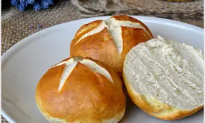 Na talerzu leżą dwie bułki bawarskie, jedna przekrojona na pół, ukazująca puszysty środek.