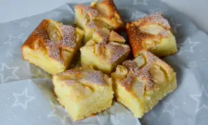 Sześć kawałków pysznego, szybkiego i taniego ciasta na dużą blachę z jabłkami, posypane cukrem pudrem.