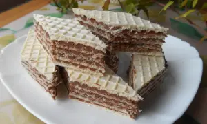 Trójkątne wafle przełożone kremem z mleka w proszku, ułożone na białym talerzu.