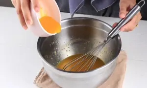 Dodawanie żółtka do miski z ubijaczką, przygotowanie do pysznego deseru kogel mogel.