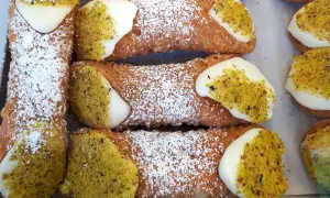 Chrupiące rurki z kremem i pistacjami, posypane cukrem pudrem. Pyszne cannoli czekają!