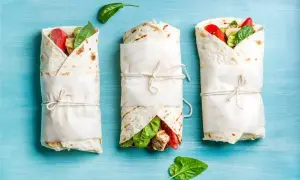 Trzy tortille zawinięte w papier, z widocznym nadzieniem z kurczaka, pomidorów i szpinaku. Idealne na keto tortilla przepis.