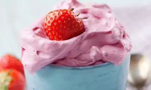 Puszysty krem truskawkowy do tortu z mrożonych truskawek, udekorowany świeżą truskawką.
