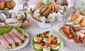 Udekorowany stół na śniadanie wielkanocne: babka, baranek, jajka faszerowane, wędliny i ciasto.