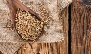 Drewniana łyżka pełna ziaren orkiszu na płótnie. Czy mąka orkiszowa ma gluten? Tak, orkisz zawiera gluten.