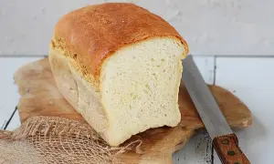 Świeżo upieczony chleb tostowy na desce, obok nóż do chleba. Idealny na śniadanie.