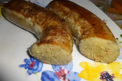 Dwie złociste kiszki ziemniaczane, pieczone do perfekcji, leżą na talerzu z kolorowymi kwiatami.