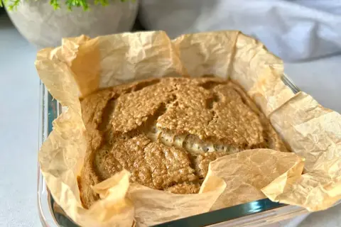 Świeżo upieczony bochenek pieczywa keto, pachnący i złocisty, w papierze do pieczenia. Idealny na śniadanie.