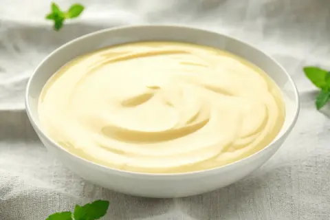 Gładki, kremowy custard w miseczce, ozdobiony listkami mięty. Pyszny deser, który rozgrzewa serce.