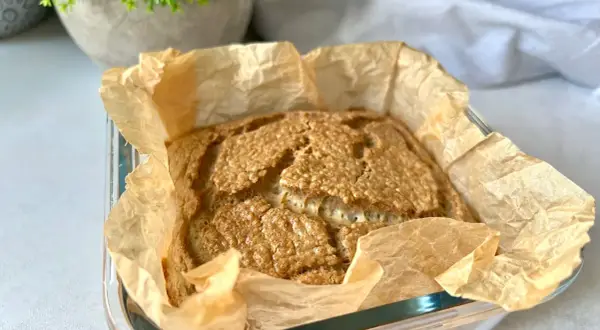 Świeżo upieczony bochenek pieczywa keto, pachnący i złocisty, w papierze do pieczenia. Idealny na śniadanie.
