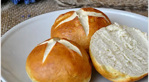 Na talerzu leżą dwie bułki bawarskie, jedna przekrojona na pół, ukazująca puszysty środek.