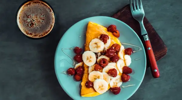 Słodki omlet z bananem i malinami, polany miodem. Idealny przepis na omlet na słodko na śniadanie.