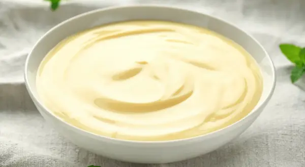 Gładki, kremowy custard w miseczce, ozdobiony listkami mięty. Pyszny deser, który rozgrzewa serce.