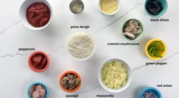 Pinsa z czym zrobić? Składniki: sos, parmezan, ciasto, pepperoni, szynka, kiełbaska, mozzarella, kukurydza, oliwki, pieczarki, papryka, cebula.