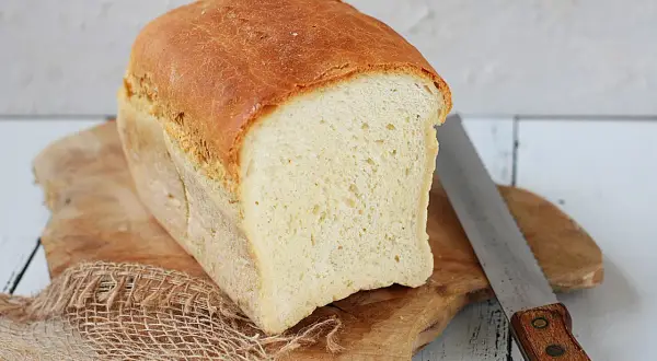 Świeżo upieczony chleb tostowy na desce, obok nóż do chleba. Idealny na śniadanie.