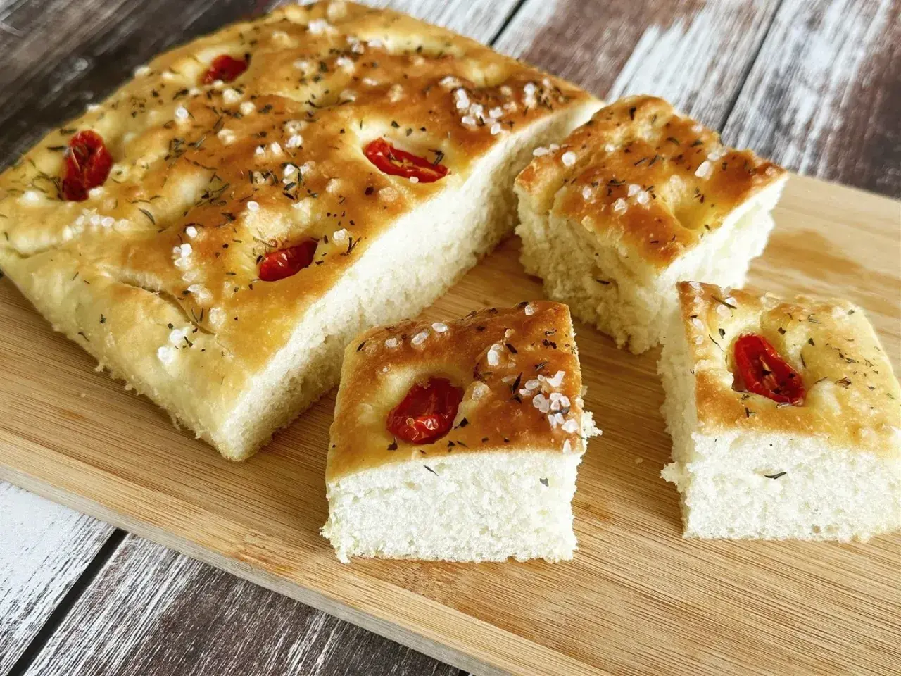 Puszysta, oryginalna włoska focaccia przepis z pomidorkami i solą morską, pokrojona na kawałki, gotowa do degustacji.