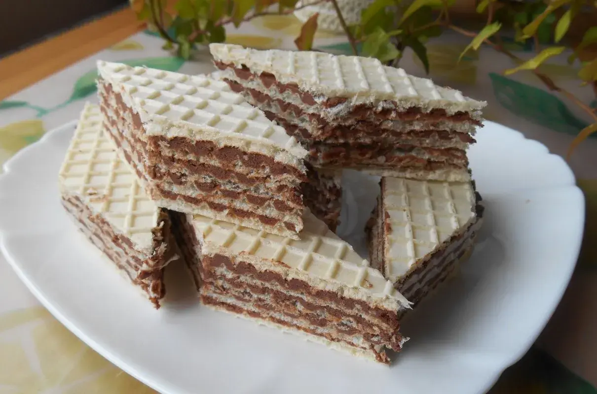 Trójkątne wafle przełożone kremem z mleka w proszku, ułożone na białym talerzu.