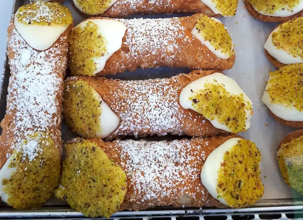 Chrupiące rurki z kremem i pistacjami, posypane cukrem pudrem. Pyszne cannoli czekają!
