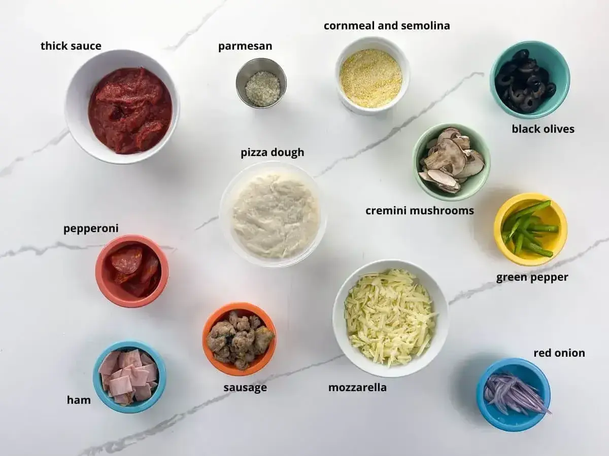 Pinsa z czym zrobić? Składniki: sos, parmezan, ciasto, pepperoni, szynka, kiełbaska, mozzarella, kukurydza, oliwki, pieczarki, papryka, cebula.