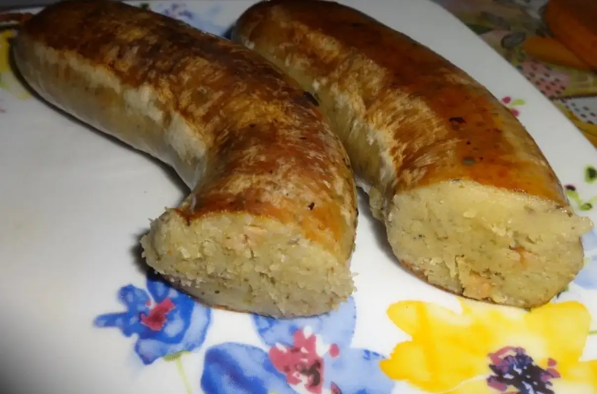 Dwie złociste kiszki ziemniaczane, pieczone do perfekcji, leżą na talerzu z kolorowymi kwiatami.