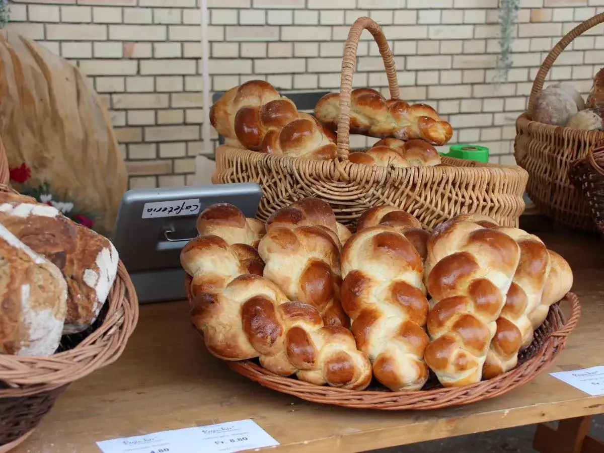 Koszyk pełen złocistej chały, obok inne pieczywo.