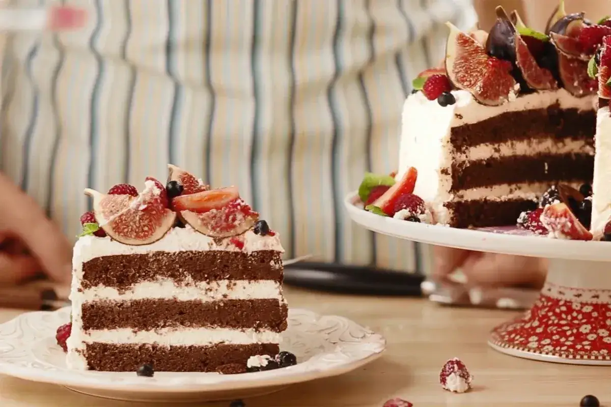 Obłędny tort czekoladowy z mascarpone i owocami: kawałek na talerzyku, cały tort na paterze, ozdobione figami, malinami i borówkami.