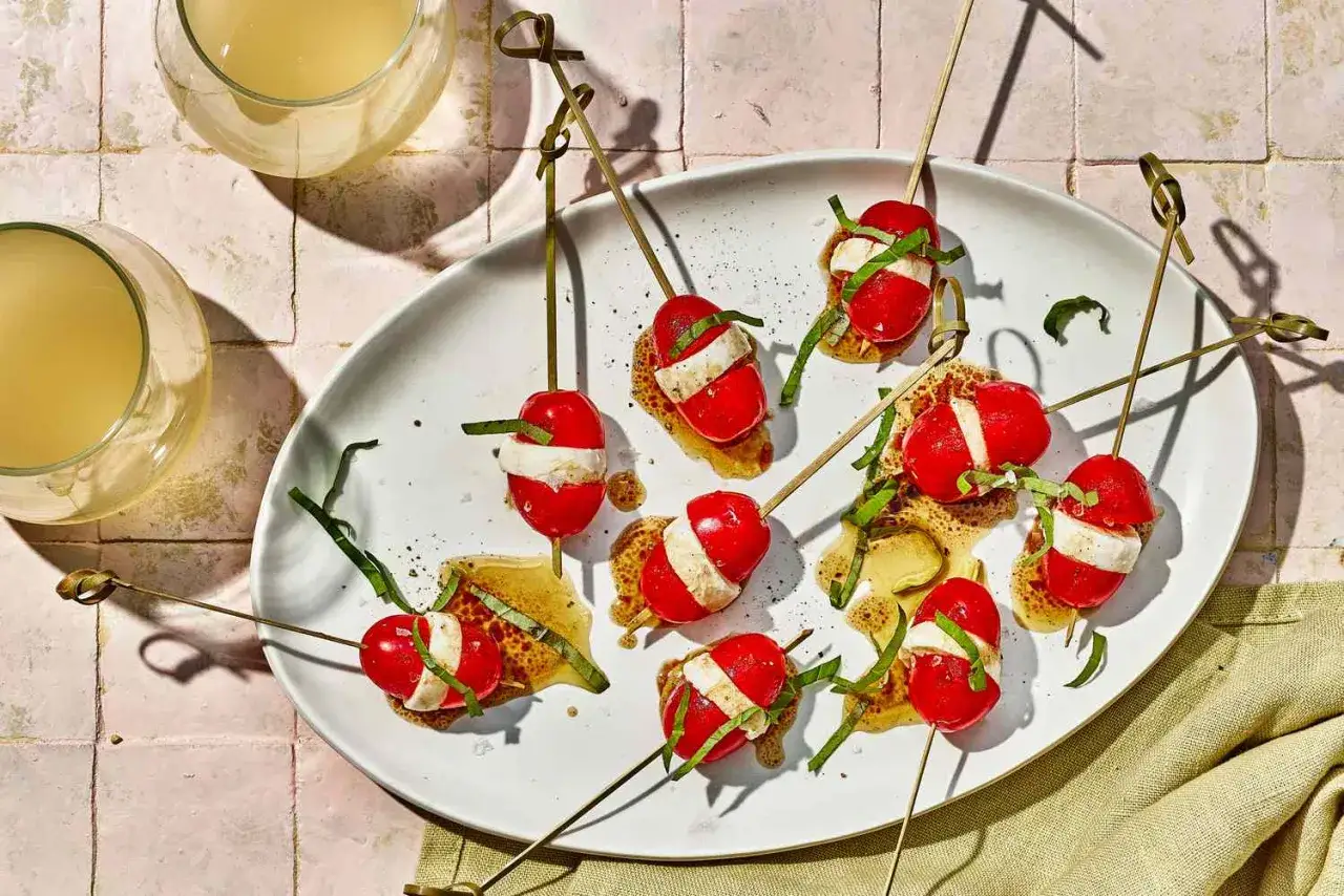 Pyszne caprese na patyczkach, idealne jako finger food. Pomidorki koktajlowe z mozzarellą i bazylią, polane sosem.