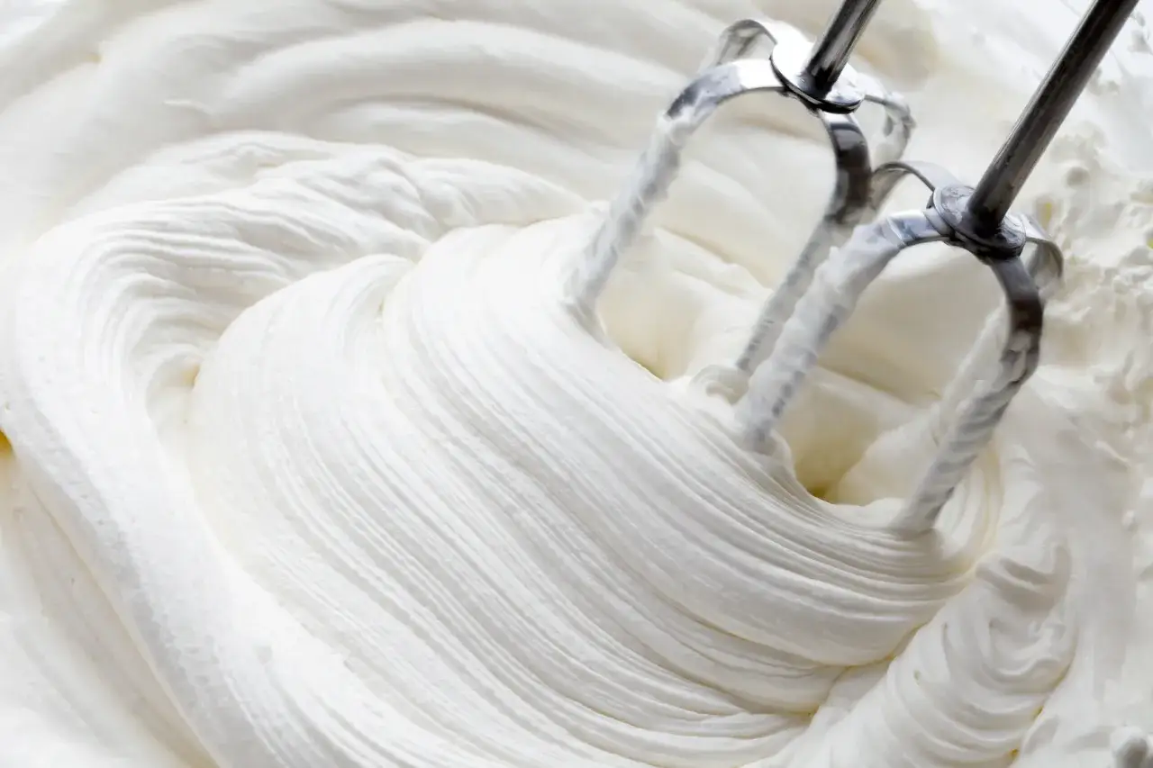 Mieszadła miksera ubijają kremową masę. Idealna bita śmietana na deser, oto jak zrobić ją szybko i łatwo.
