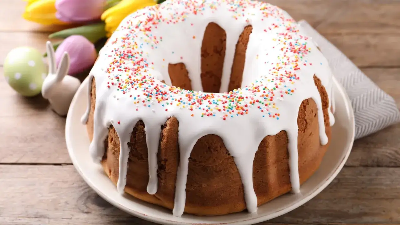 Babka z lukrem i kolorową posypką, ozdobiona wielkanocnymi zajączkami i pisankami.