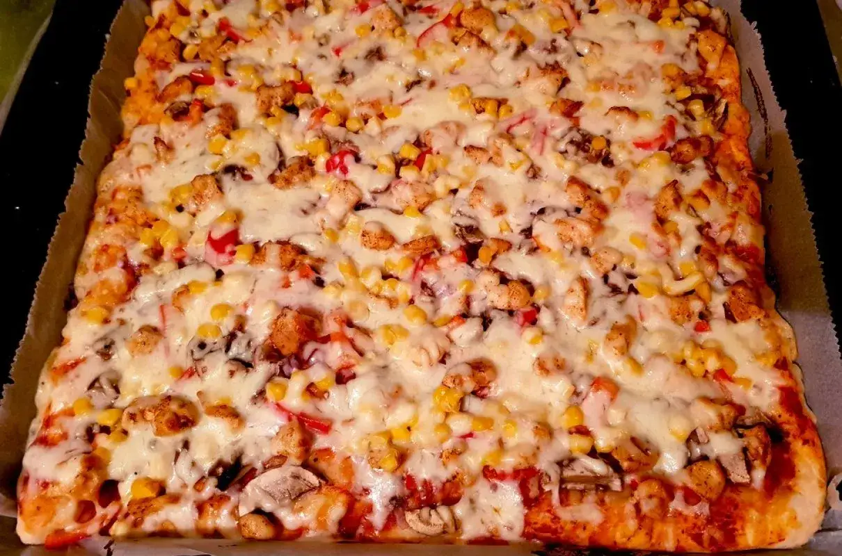 Proste ciasto na pizzę zawsze wychodzi! Ta prostokątna pizza z kurczakiem, kukurydzą i pieczarkami, obficie posypana serem, wygląda pysznie.