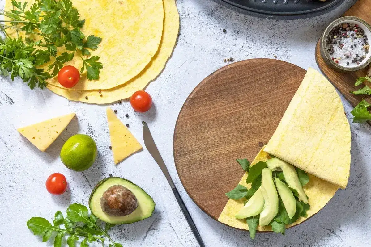 Keto tortilla przepis: składniki do wrapów z awokado, pomidorkami, serem i rukolą.