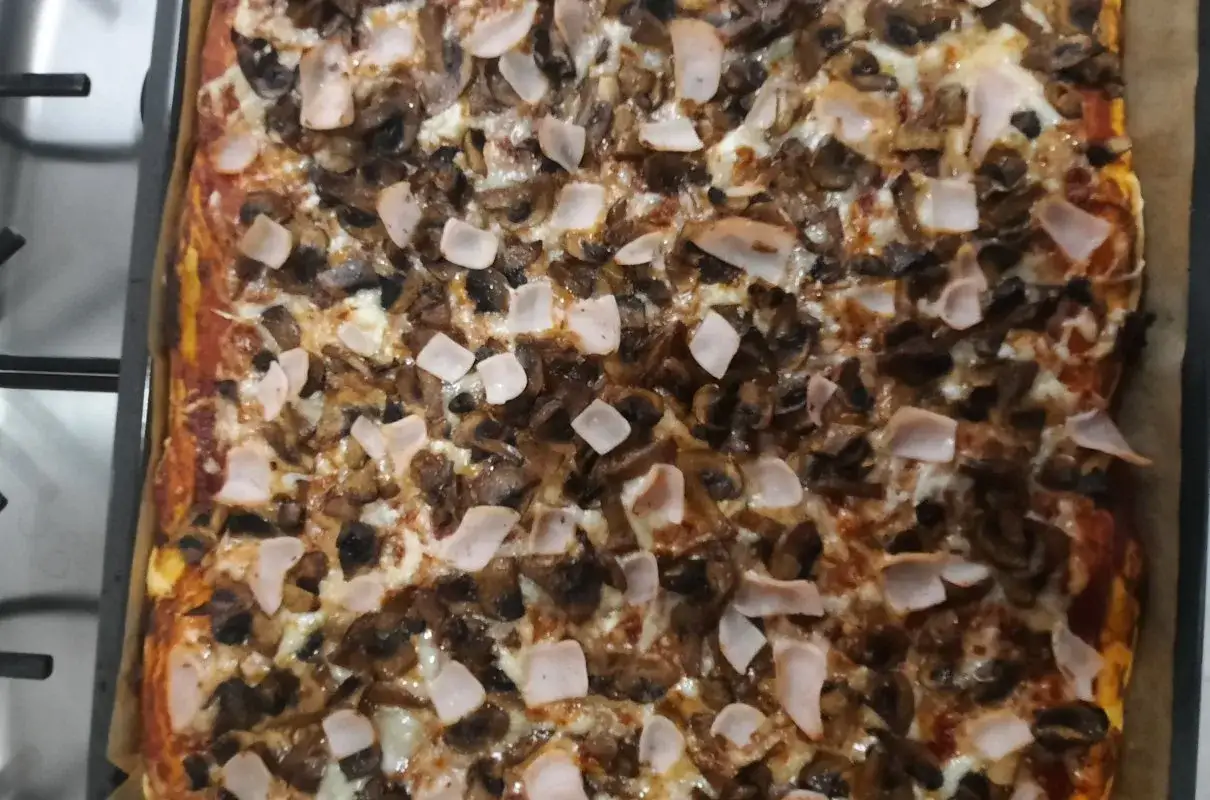 Pyszny przepis na pizzę z pieczarkami i szynką, prosto z pieca. Idealna na rodzinny obiad.