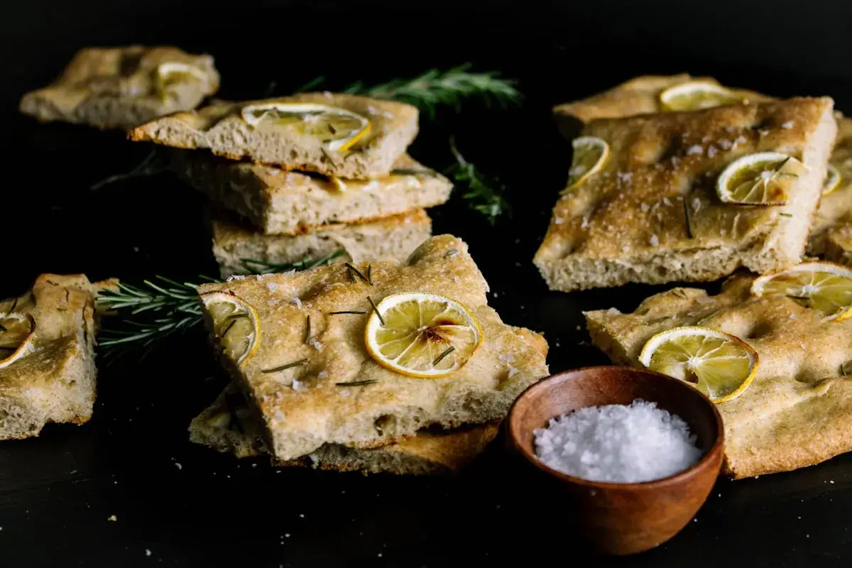 Oryginalna włoska focaccia przepis: puszyste ciasto z plasterkami cytryny i rozmarynem, posypane solą. Idealna do chrupania.