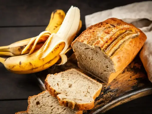 Wilgotne ciasto bananowe, obok dojrzałych bananów, kusi apetycznym wyglądem. Idealne na deser lub śniadanie.