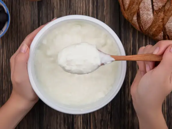 Gęsty, biały jogurt na drewnianej łyżce. To właśnie skyr, islandzki przysmak, który świetnie smakuje z chlebem i oliwkami.