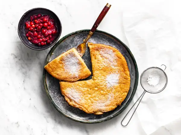 Puszysty omlet, posypany cukrem pudrem, z żurawiną obok. Idealny przepis na pyszne śniadanie.