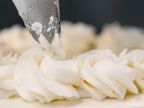 Dekorowanie tortu kremem patissiere za pomocą rękawa cukierniczego.