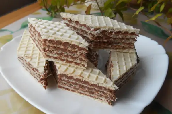 Trójkątne wafle przełożone kremem z mleka w proszku, ułożone na białym talerzu.