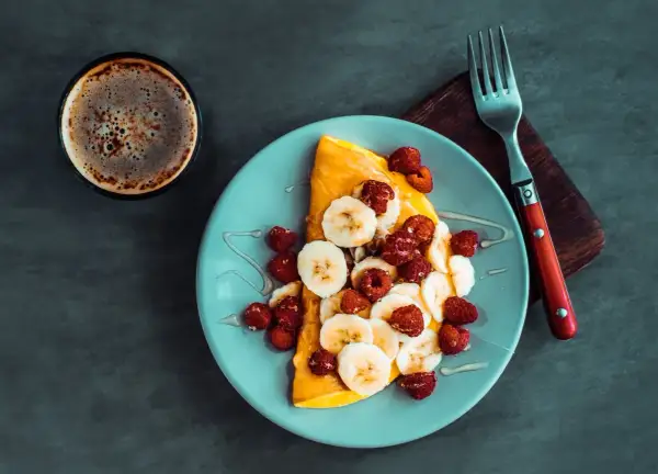 Słodki omlet z bananem i malinami, polany miodem. Idealny przepis na omlet na słodko na śniadanie.