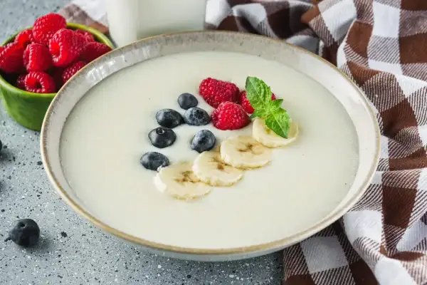 Idealne proporcje kaszy manny na mleku, podanej z malinami, borówkami i bananem. Pyszne śniadanie.