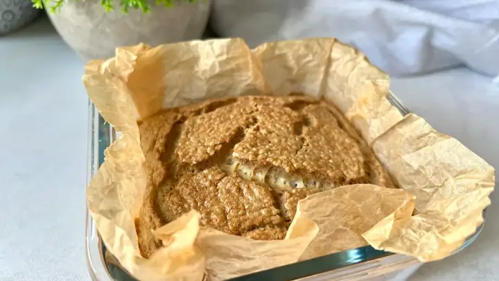 Świeżo upieczony bochenek pieczywa keto, pachnący i złocisty, w papierze do pieczenia. Idealny na śniadanie.
